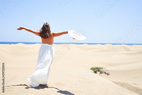 Young beautiful woman sunbathing with open arms enjoying summer vacation at maspalomas dunes beach photo
