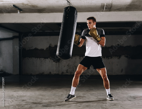 Young caucasian Boxer training with a punching bag in his home gym