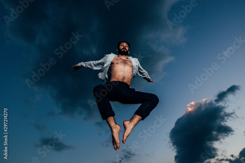 Silhouette of fashionable man while jumping during evening