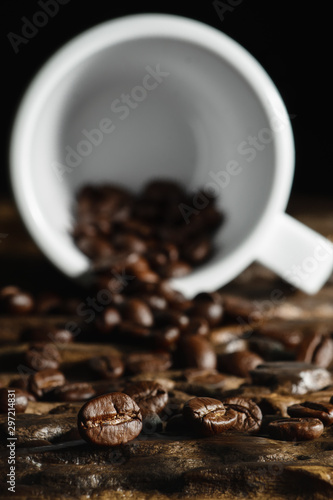 beverage background of roasted coffee beans with laying coffee cup on wooden table