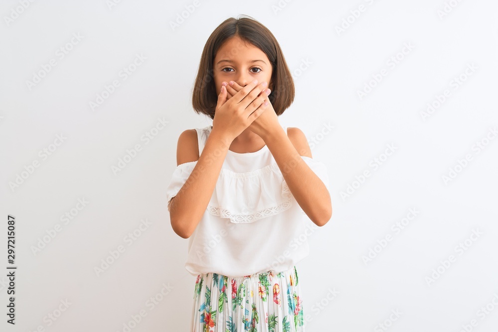 Young beautiful child girl wearing casual dress standing over isolated white background shocked covering mouth with hands for mistake. Secret concept. Young beautiful child girl wearing casual dress standing over isolated white background shocked covering mouth with hands for mistake. Secret concept.