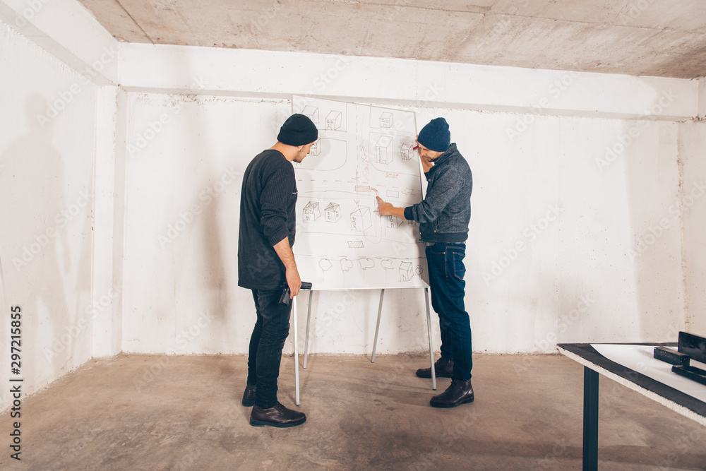 Burglars making plans for crime in basement Burglars making plans for crime in basement