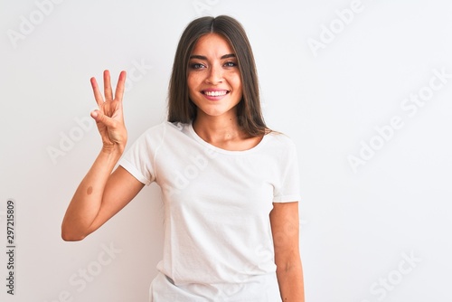 Young beautiful woman wearing casual t-shirt standing over isolated white background showing and pointing up with fingers number three while smiling confident and happy. © Krakenimages.com