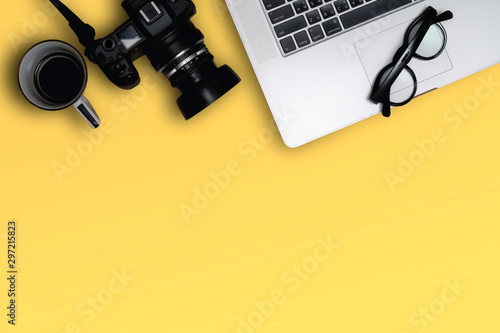 Flat lay, top view of laptop, photography device and cooffe cup on clean yellow color table. image create blank copy space. photo