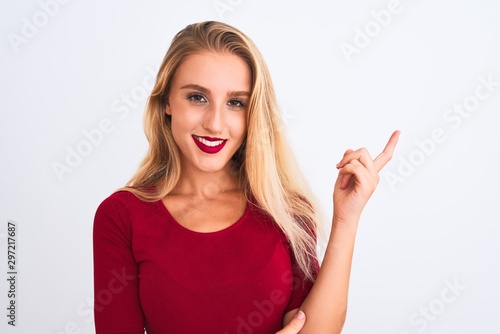 Young beautiful woman wearing red t-shirt standing over isolated white background very happy pointing with hand and finger to the side