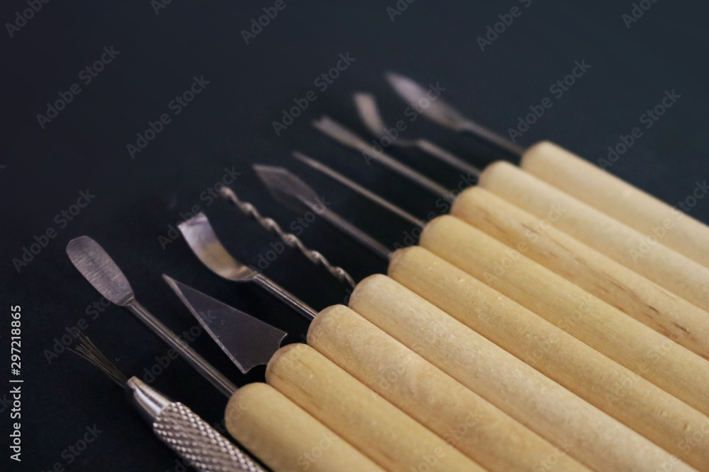 Set of sculpture tools of metal and wood with different tips for modeling on a black background Set of sculpture tools of metal and wood with different tips for modeling on a black background