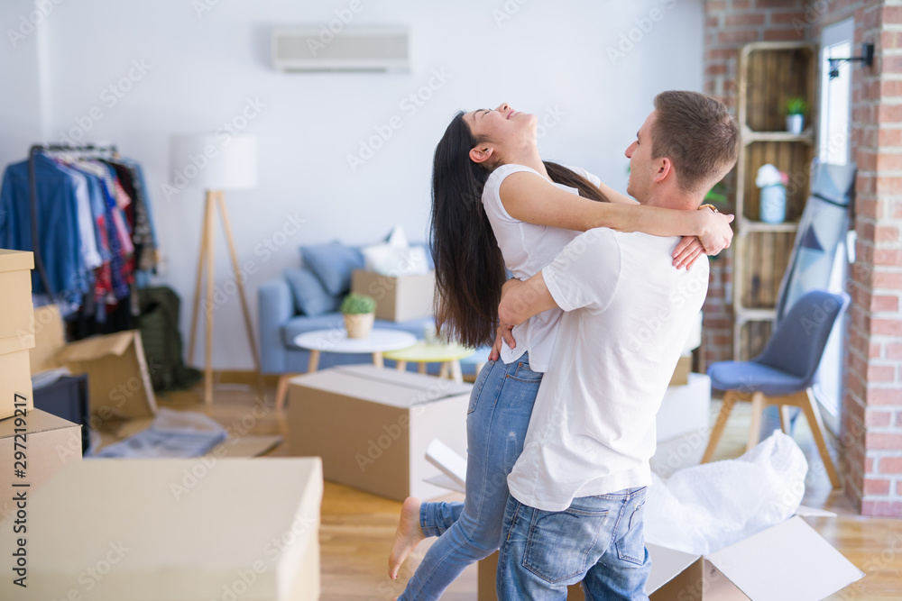 Young beautiful couple hugging at new home around cardboard boxes Young beautiful couple hugging at new home around cardboard boxes