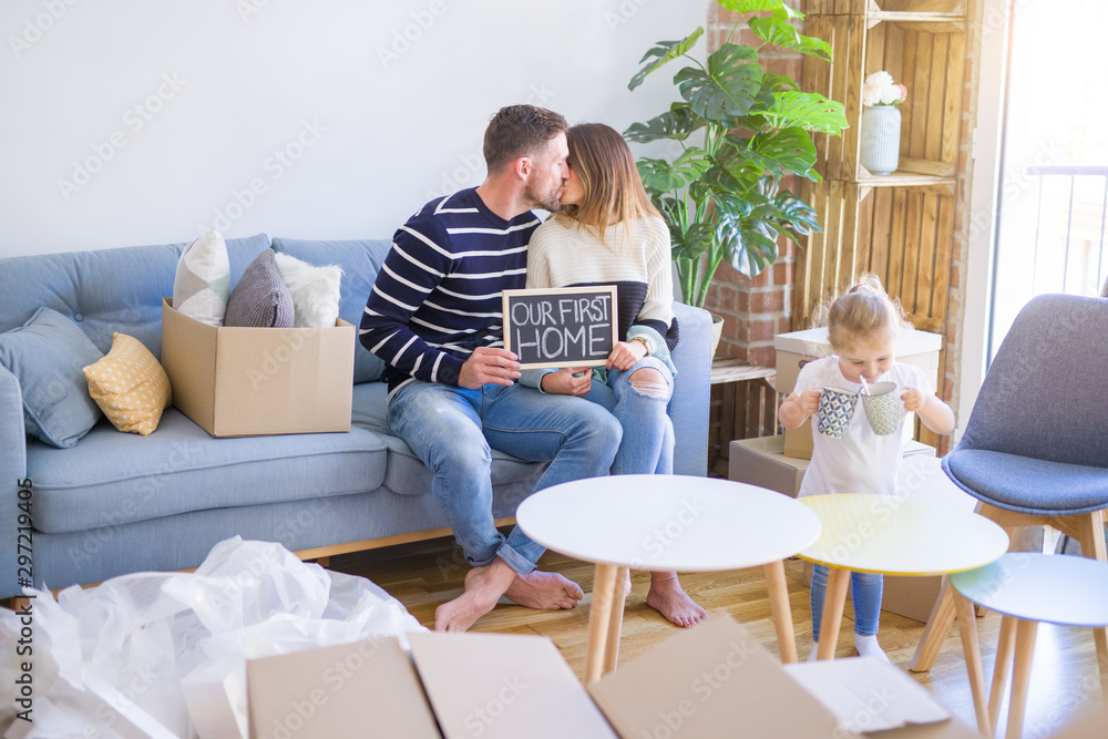Beautiful famiily with kid sitting on the sofa holding blackboard at new home around cardboard boxes Beautiful famiily with kid sitting on the sofa holding blackboard at new home around cardboard boxes