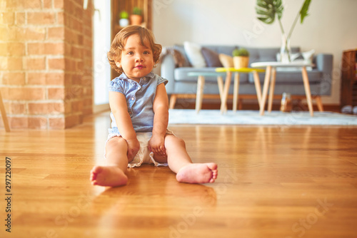 Beautiful toddler child girl wearing blue denim shirt sitting on the floor