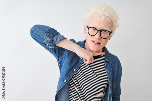 Young albino blond man wearing denim shirt and glasses over isolated white background cutting throat with hand as knife, threaten aggression with furious violence