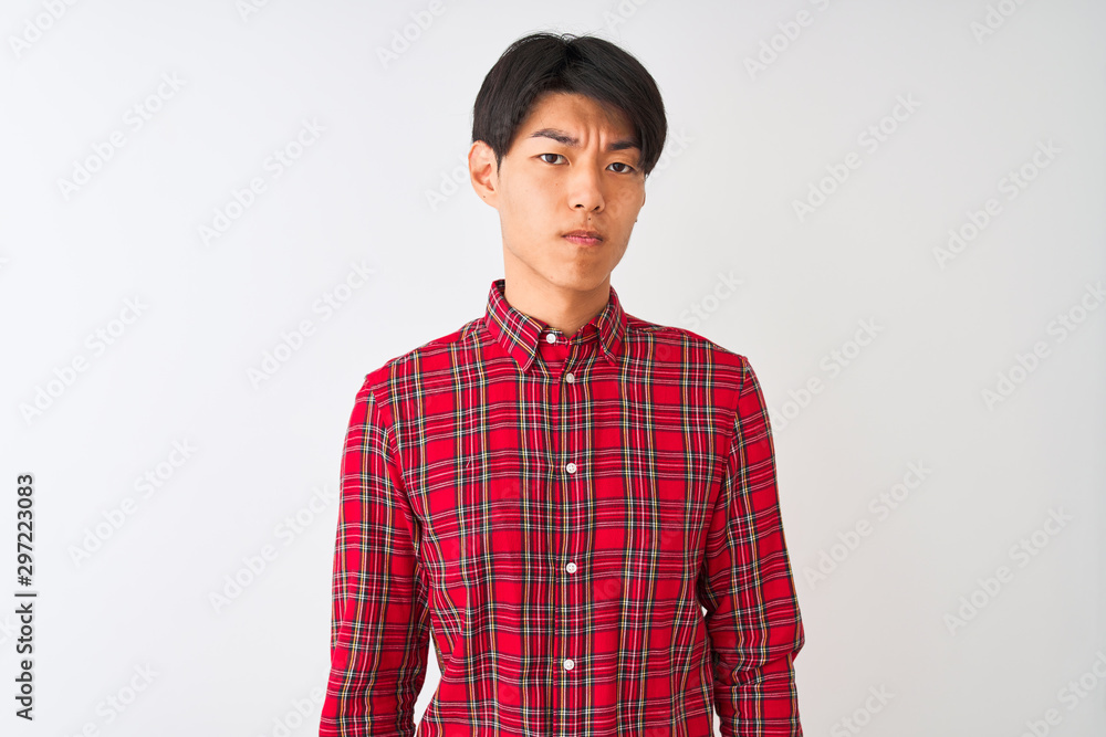 Young chinese man wearing casual red shirt standing over isolated white background skeptic and nervous, frowning upset because of problem. Negative person. Young chinese man wearing casual red shirt standing over isolated white background skeptic and nervous, frowning upset because of problem. Negative person.