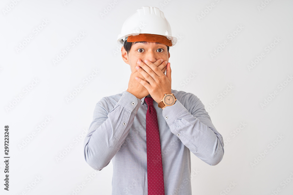 Chinese architect man wearing tie and helmet standing over isolated white background shocked covering mouth with hands for mistake. Secret concept. Chinese architect man wearing tie and helmet standing over isolated white background shocked covering mouth with hands for mistake. Secret concept.