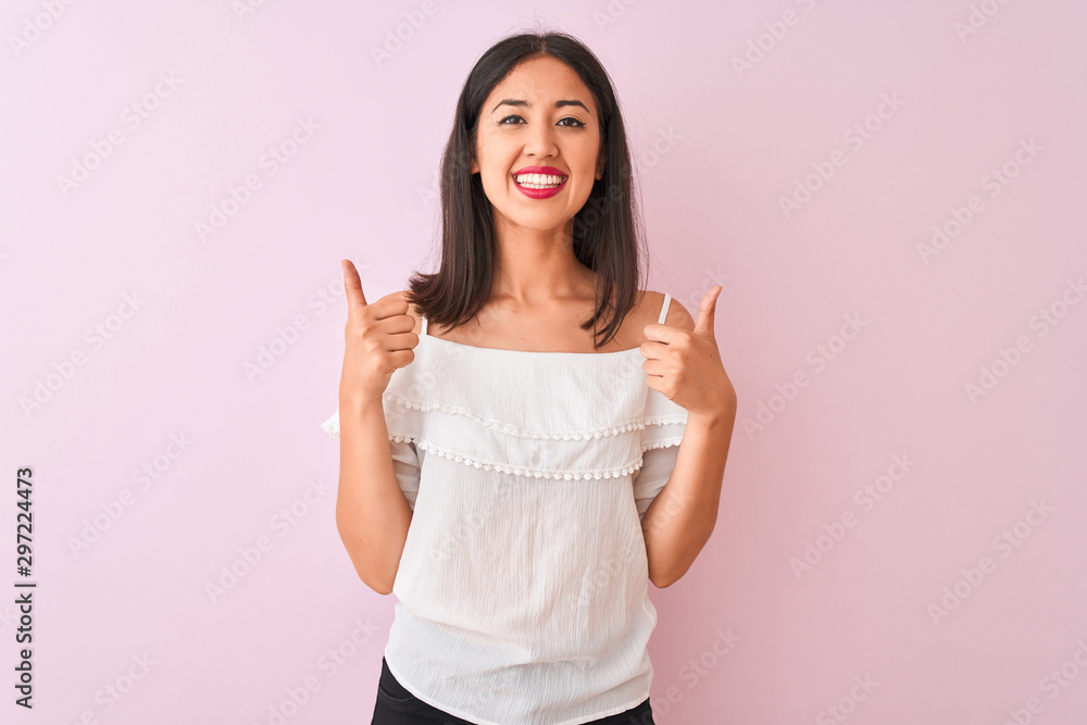 Beautiful chinese woman wearing white t-shirt standing over isolated pink background success sign doing positive gesture with hand, thumbs up smiling and happy. Cheerful expression and winner gesture. Beautiful chinese woman wearing white t-shirt standing over isolated pink background success sign doing positive gesture with hand, thumbs up smiling and happy. Cheerful expression and winner gesture.