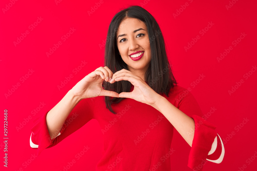 Young beautiful chinese woman wearing casual dress standing over isolated red background smiling in love showing heart symbol and shape with hands. Romantic concept. Young beautiful chinese woman wearing casual dress standing over isolated red background smiling in love showing heart symbol and shape with hands. Romantic concept.