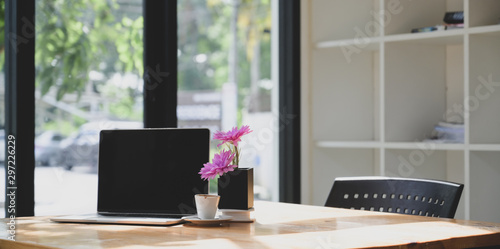 Open blank screen laptop computer in comfortable workspace with pink flower