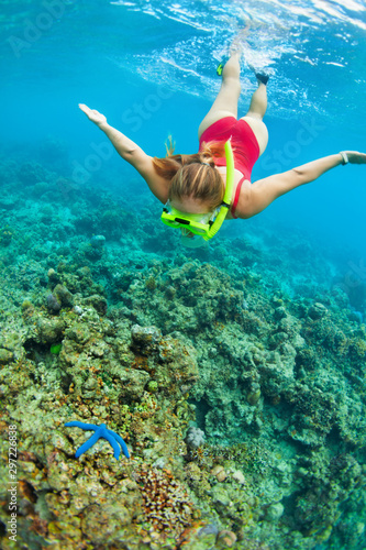 Happy family - active woman in snorkeling mask dive underwater, see tropical fishes in coral reef sea pool. Travel adventure, swimming activity and watersports on summer beach vacation with child.