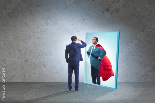 Businessman seeing himself in mirror as superhero photo