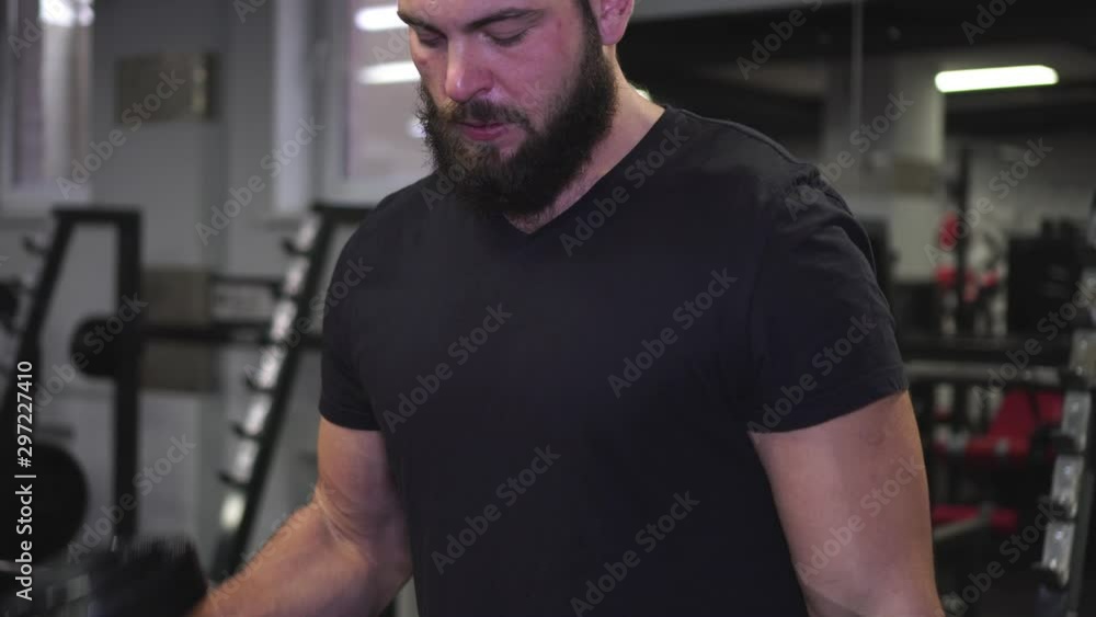 Brutal man with a beard lifts large dumbbells in the gym. Brutal man with a beard lifts large dumbbells in the gym.