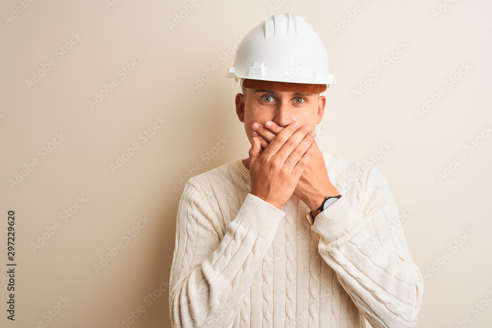 Handsome architect man wearing security helmet standing over isolated white background shocked covering mouth with hands for mistake. Secret concept. Handsome architect man wearing security helmet standing over isolated white background shocked covering mouth with hands for mistake. Secret concept.