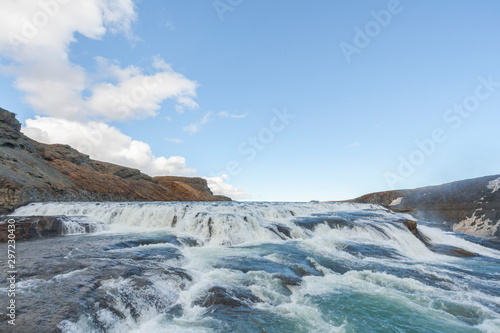 A three-step staircase of the Gullfoss waterfall on Hvita river, as pictured in detail (water plunging into the canyon, mossy cliffs, thick spray, panorama of the rapids)