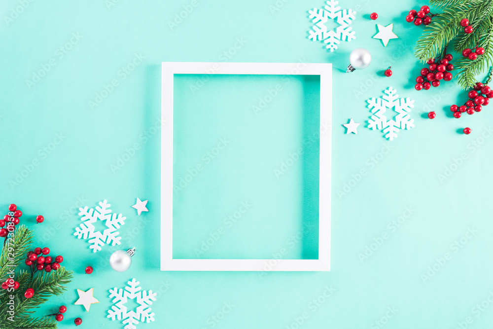 Christmas holidays composition Top view of white picture frame with Christmas tree decoration and red berries on green pastel background with copy space for text. Christmas holidays composition Top view of white picture frame with Christmas tree decoration and red berries on green pastel background with copy space for text.