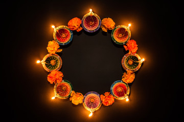 Happy Diwali - Clay Diya lamps lit during Dipavali, Hindu festival of lights celebration. Colorful traditional oil lamp diya on black background