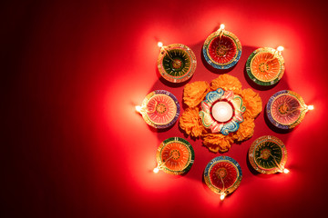 Happy Diwali - Clay Diya lamps lit during Dipavali, Hindu festival of lights celebration. Colorful traditional oil lamp diya on pink background