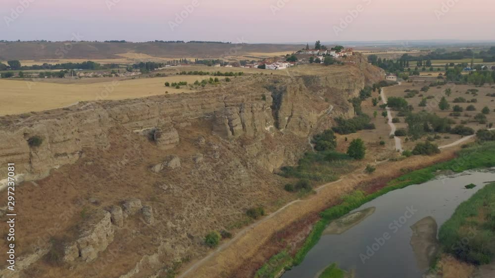 Drone flying forward over river and canyon, with small town at the bottom at summer sunset Drone flying forward over river and canyon, with small town at the bottom at summer sunset