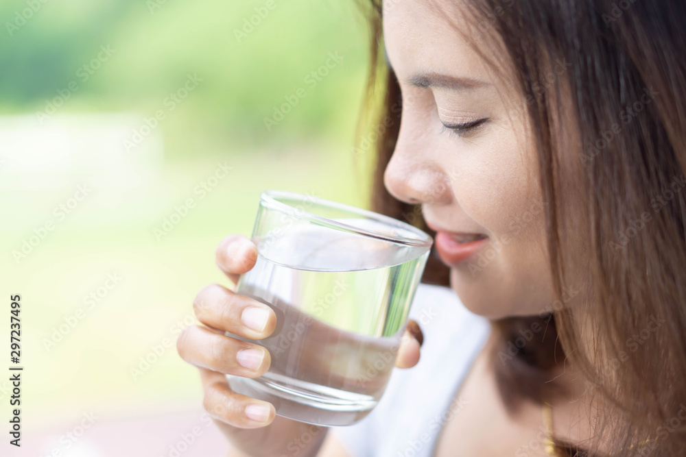 Close up woman drinking pure water from glass with light in the morning, Selective focus Close up woman drinking pure water from glass with light in the morning, Selective focus