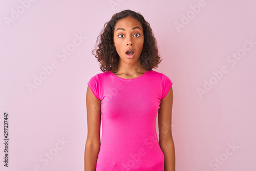 Young brazilian woman wearing t-shirt standing over isolated pink background afraid and shocked with surprise expression  fear and excited face.