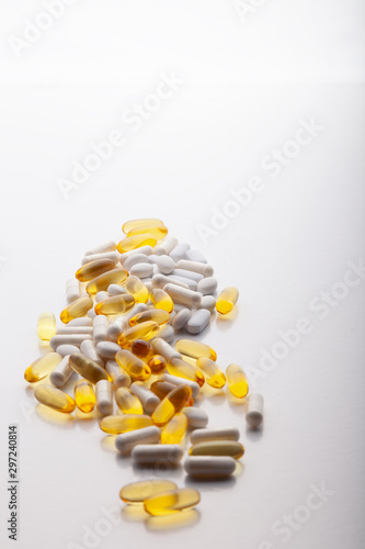 Tablets, pills, capsules, drugs pouring out of white bottle on white background. Sport, healthy lifestyle, medicine, nutritional supplements, people concept - closeup fish oil capsules soft gel