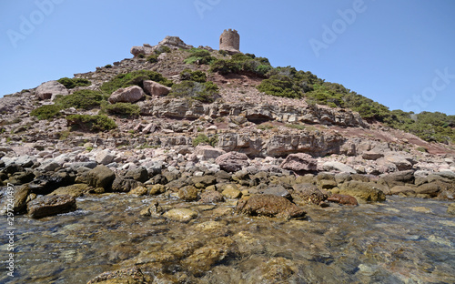 Scenic view of the rocky hill on the Sardinian sea near Torre del Porticciolo beach, with an ancient lookout tower on the top, on a sunny summer day