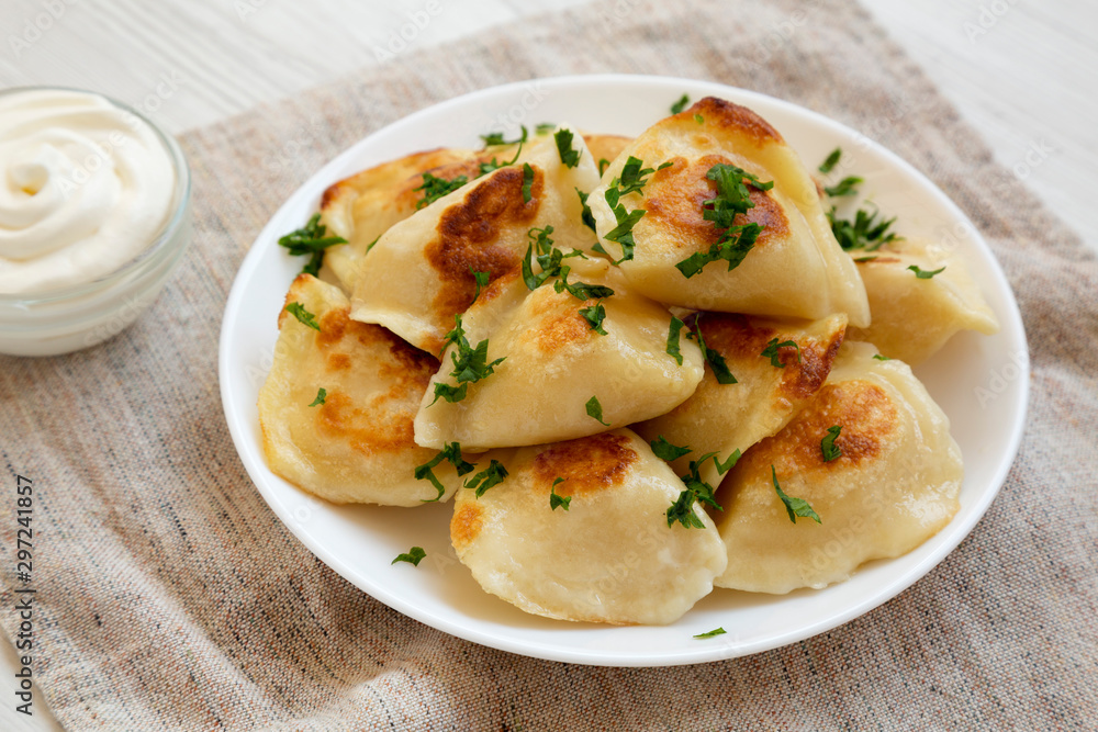 Homemade traditional polish fried potato pierogies on a white plate, side view. Close-up. Homemade traditional polish fried potato pierogies on a white plate, side view. Close-up.