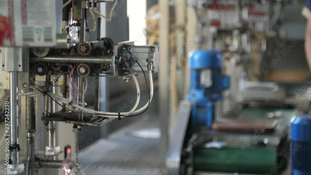 Modern robots working on a tomato plant conveyor with falling ketchup packages Modern robots working on a tomato plant conveyor with falling ketchup packages