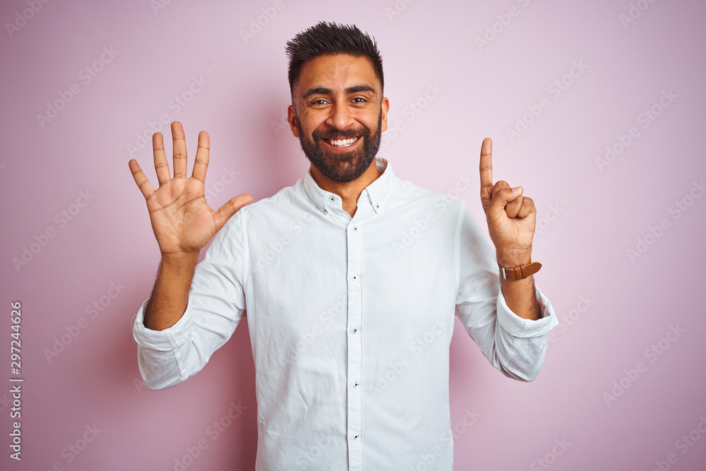 Young indian businessman wearing elegant shirt standing over isolated pink background showing and pointing up with fingers number six while smiling confident and happy. Young indian businessman wearing elegant shirt standing over isolated pink background showing and pointing up with fingers number six while smiling confident and happy.
