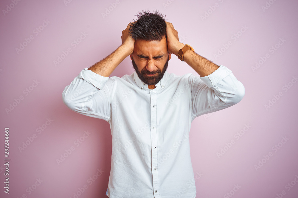 Young indian businessman wearing elegant shirt standing over isolated pink background suffering from headache desperate and stressed because pain and migraine. Hands on head. Young indian businessman wearing elegant shirt standing over isolated pink background suffering from headache desperate and stressed because pain and migraine. Hands on head.