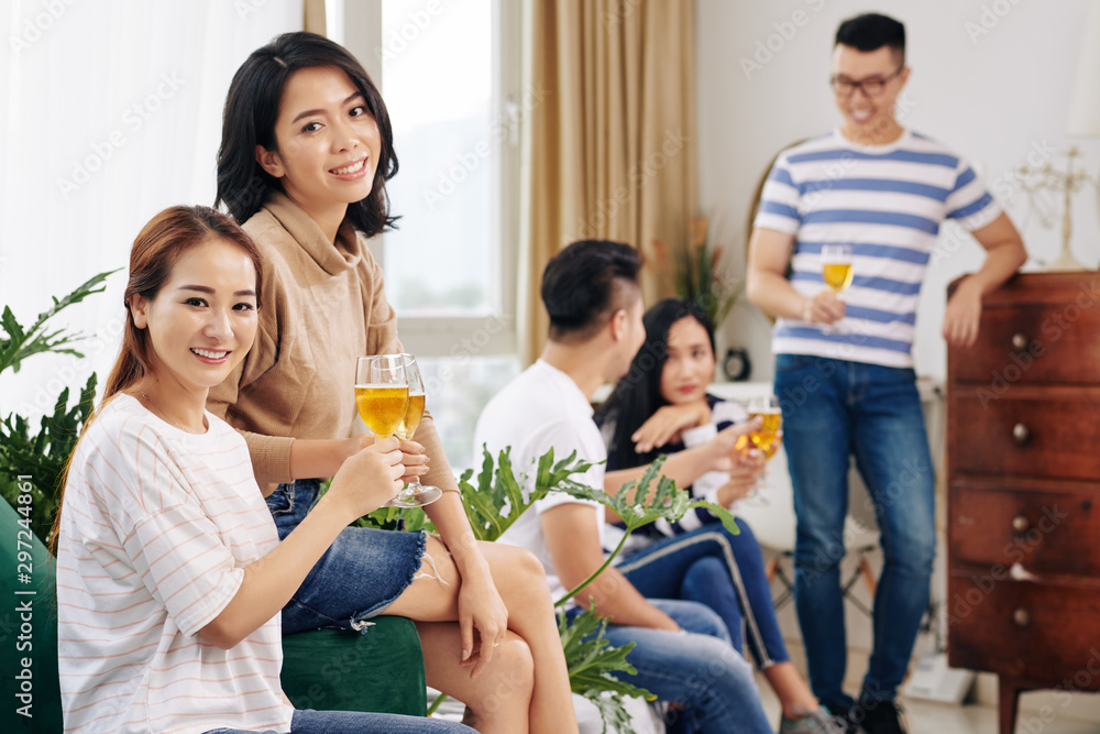 Obraz premium Pretty female friends having drinks when attending cozy party at home