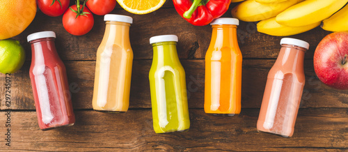 Multicoloured juices in bottles on old wooden background with fruits and vegetables. Top view. Banner