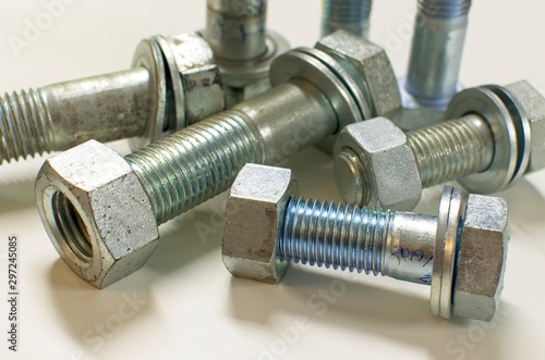 Stainless steel nuts and bolts on white background with strong defocus