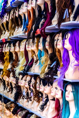 Several rows of mannequin heads wearing various colour wigs