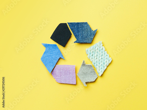 Reuse, reduce, recycle concept background. Recycle symbol made from old clothing on yellow background. Top view or flat lay. photo