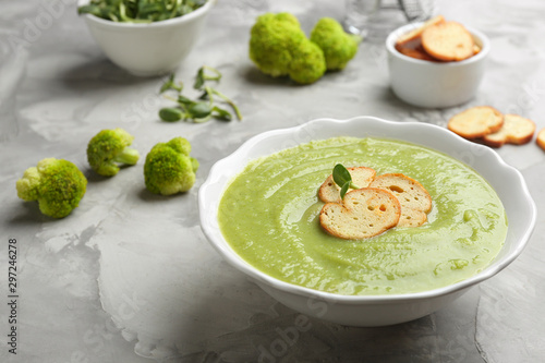 Bowl of broccoli cream soup with croutons served on grey table