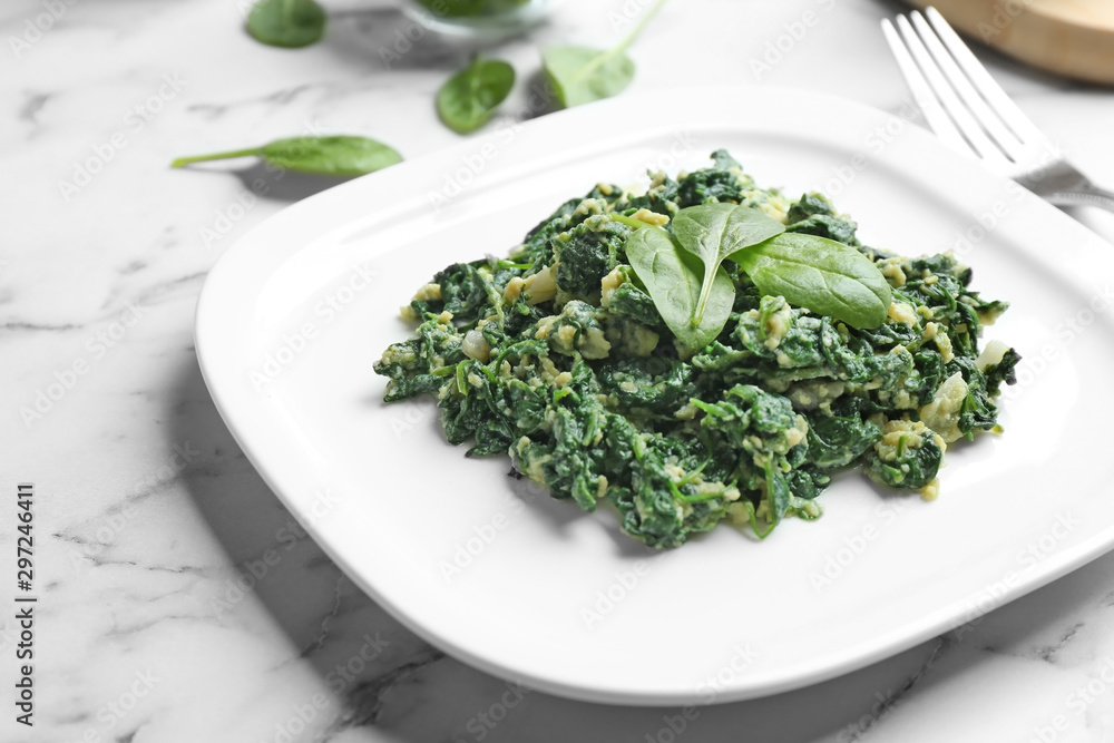 Tasty cooked spinach with scrambled eggs on white marble table, closeup. Healthy food Tasty cooked spinach with scrambled eggs on white marble table, closeup. Healthy food