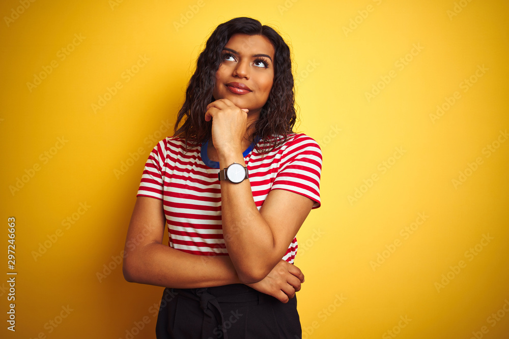 Obraz premium Transsexual transgender woman wearing stiped t-shirt over isolated yellow background with hand on chin thinking about question, pensive expression. Smiling with thoughtful face. Doubt concept.