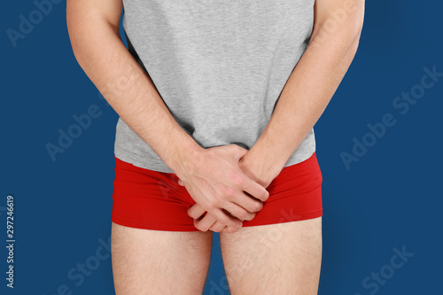 Man suffering from pain on blue background, closeup. Urology problems