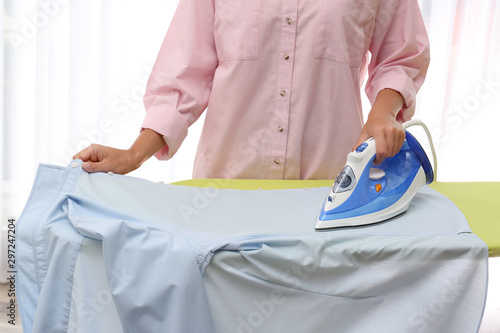 Young woman ironing clean shirt at home, closeup. Laundry day