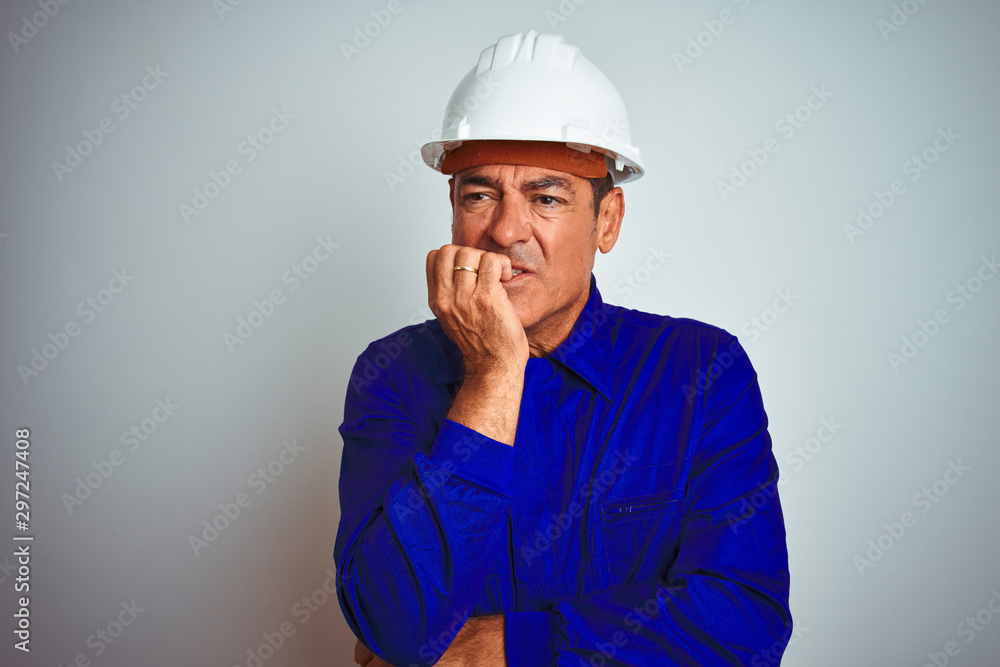Handsome middle age worker man wearing uniform and helmet over isolated white background looking stressed and nervous with hands on mouth biting nails. Anxiety problem. Handsome middle age worker man wearing uniform and helmet over isolated white background looking stressed and nervous with hands on mouth biting nails. Anxiety problem.