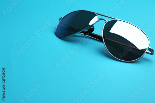 Stylish sunglasses on blue background  space for text. Fashionable accessory