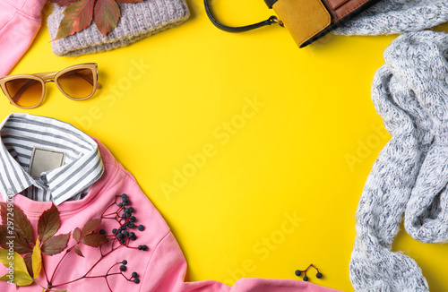 Flat lay composition with warm clothes and autumn leaves on yellow background, space for text