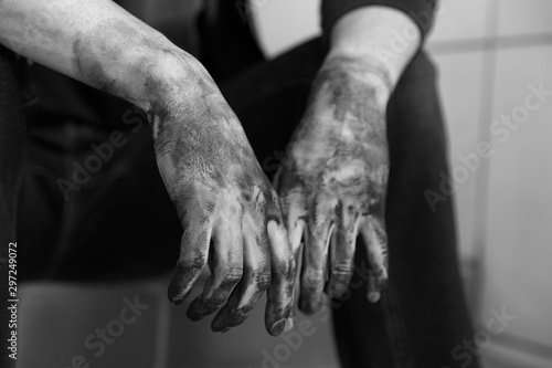 Dirty worker sitting on stairs, closeup of hands. Black and white effect